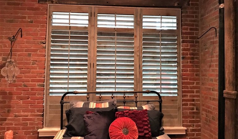 Reclaimed wood shutters give a natural touch to your minimalist spaces. Reclaimed wood shutters near a brick wall.